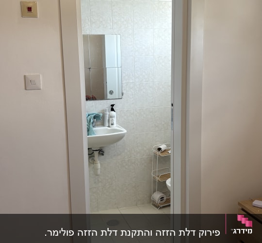 דלת כניסה לחדר אמבטיה עם כיור ומראה